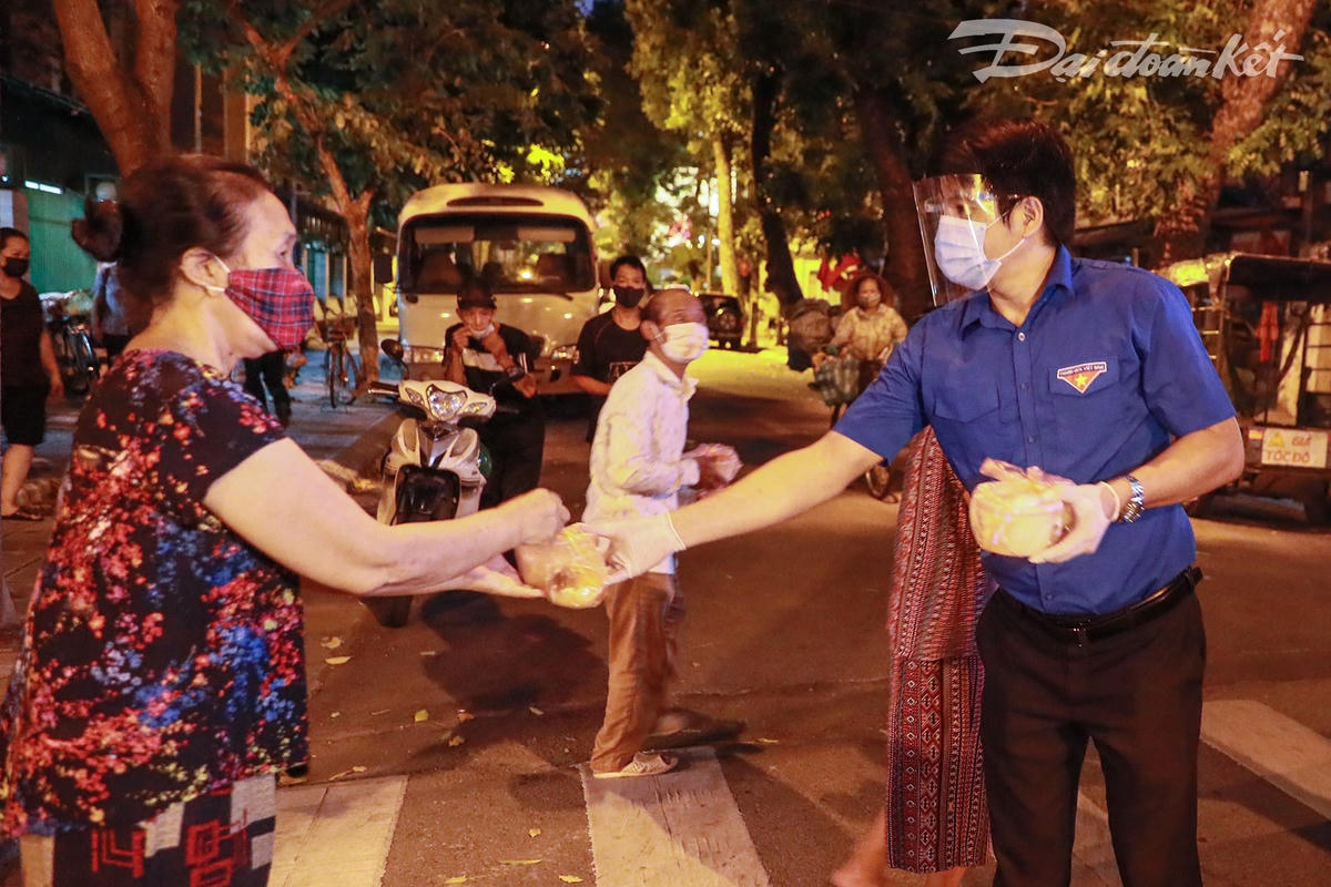 Điểm đến tiếp theo của đoàn dừng tại phố Trần Bình Trọng. Từng cụ già, bà bầu hay những người có hoàn cảnh khó khăn xếp hàng nhận từng suất ăn. Ảnh: Quang Vinh. 