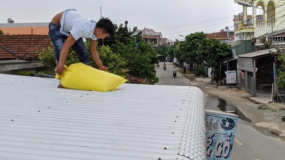 Người dân xã Phổ An (Đức Phổ, Quảng Ngãi) chèn bao nước lên mái tôn. Ảnh: Tấn Lực.