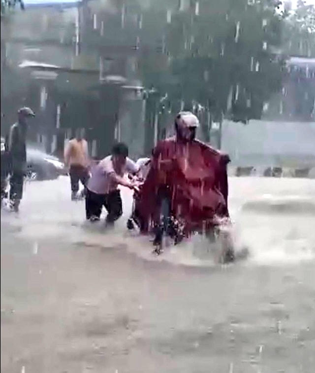 Hai em học sinh đẩy xe giúp người dân trong cơn mưa lớn.  