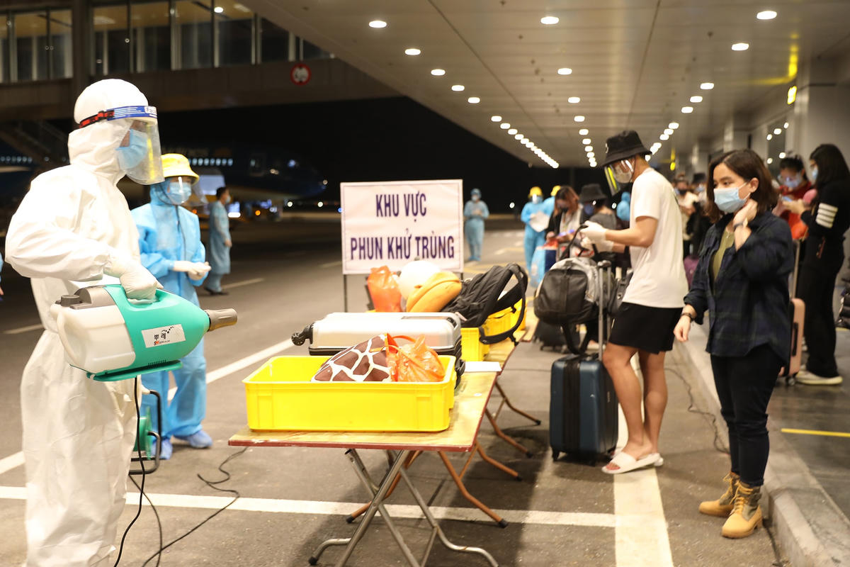 Hành lý xách tay của người từ nước ngoài về (sân bay Vân Đồn) được khử khuẩn trước khi làm thủ tục kiểm tra y tế.