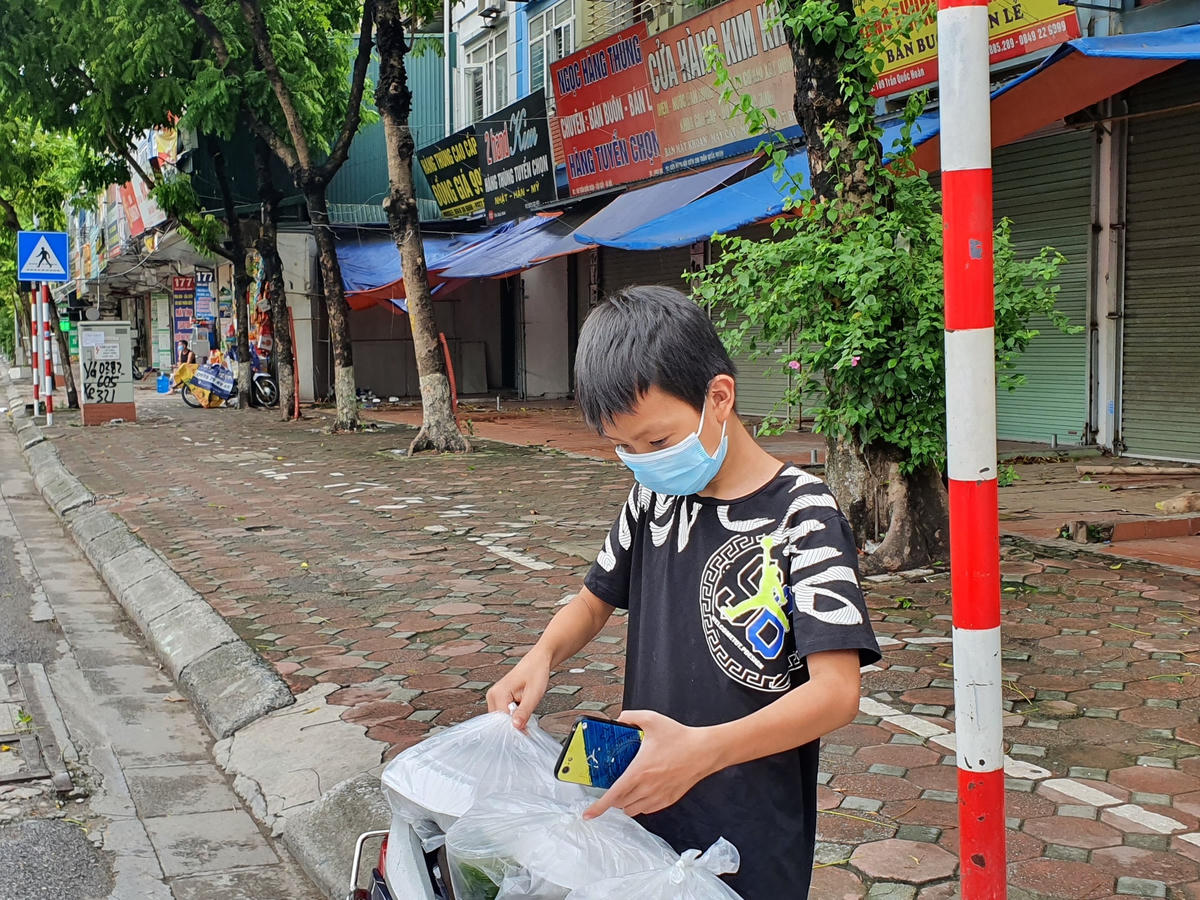 Một em bé đến điểm lấy cơm cho cả gia đình... Được biết, ngoài những suất cơm miễn phí, nhóm tình nguyện của ông Tuân còn trực tiếp hỗ trợ tiền mặt với một số hoàn cảnh khó khăn trong mùa dịch. 