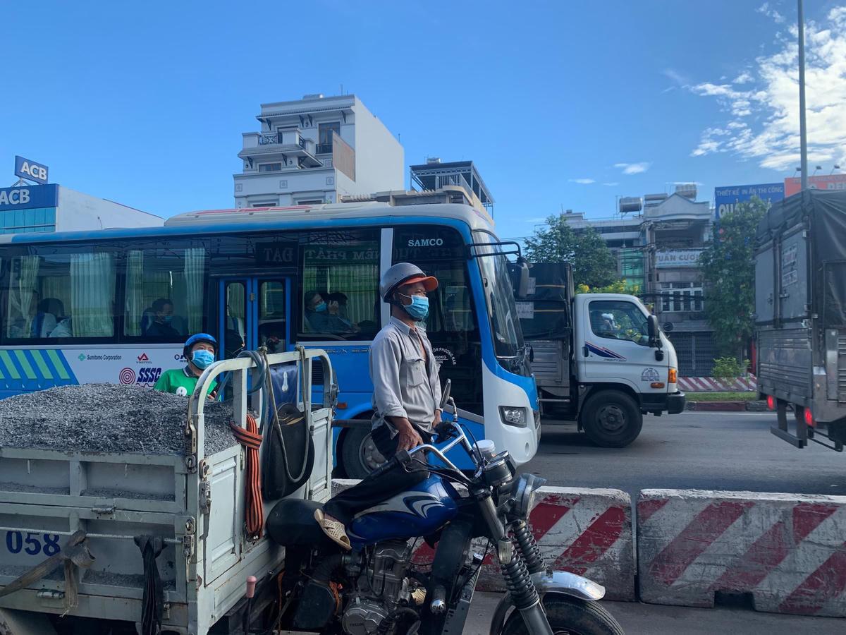 Lái xe ba gác đứng quan sát tình trạng kẹt xe để tìm đường thoát.