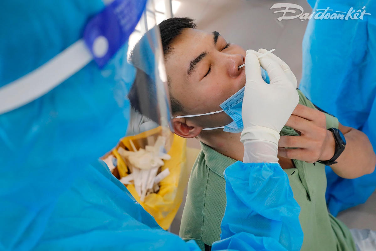 Khi lấy mẫu, người dân chỉ kéo khẩu trang để hở mũi, không hở miệng. Ảnh: Quang Vinh. 