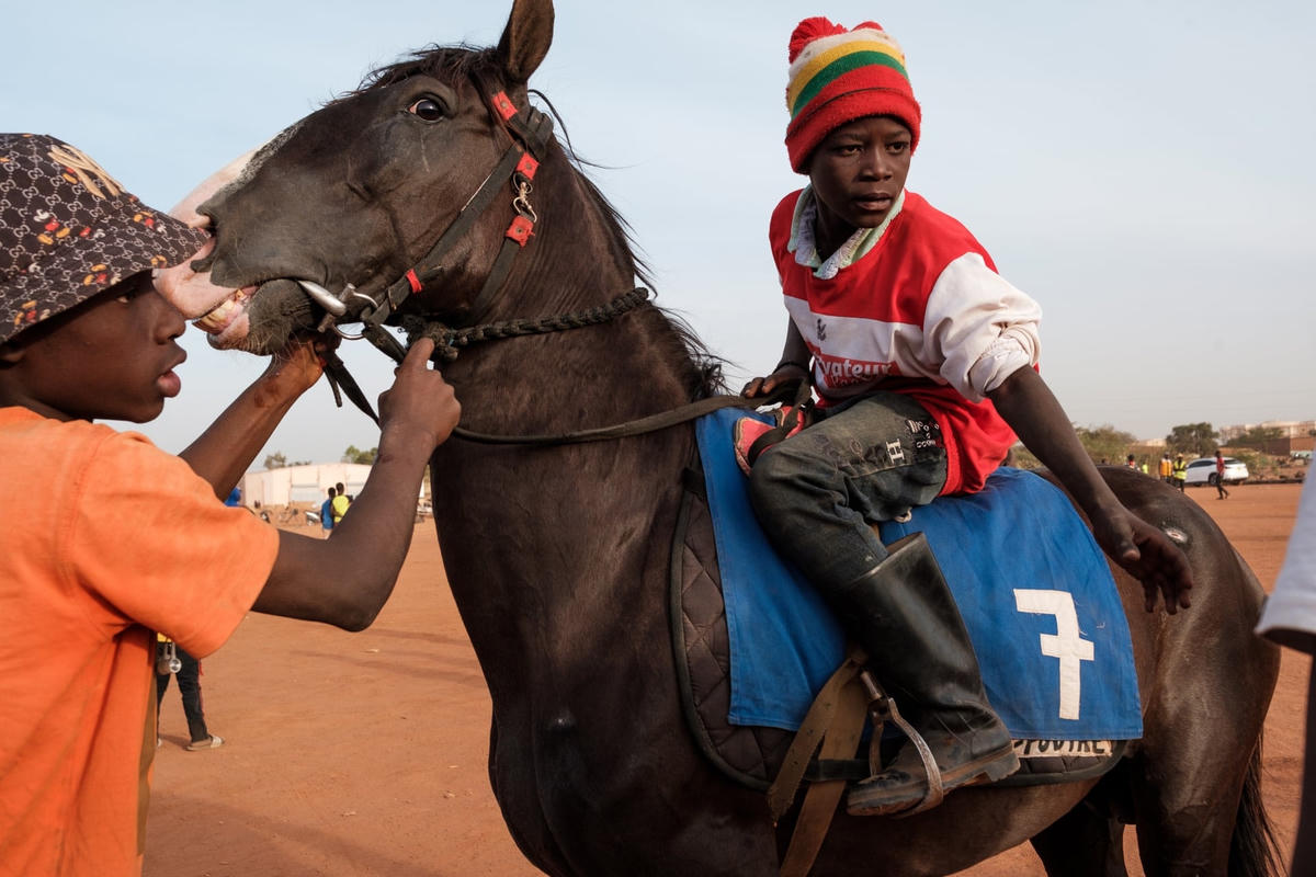 Một tay đua trẻ tuổi cầm chiếc roi được làm từ một sợi dây cáp cũ với băng keo làm tay cầm, chuẩn bị sẵn sàng cho cuộc đua. Ảnh: Guy Peterson / The Guardian.