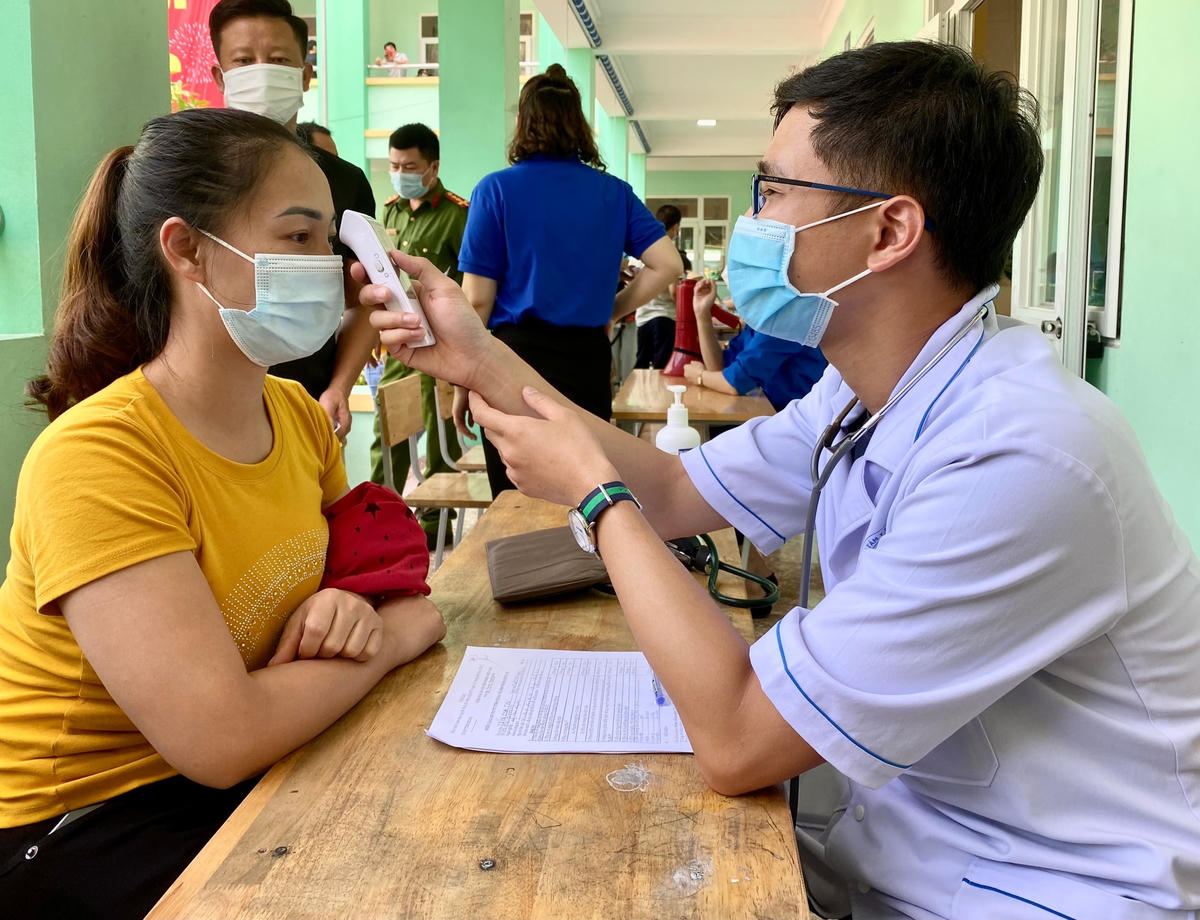 Người dân được đo thân nhiệt, khám sàng lọc trước khi tiêm.
