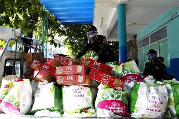 Cán bộ chiến sỹ Trung đoàn 1, Sư đoàn 9, Quân đoàn 4 vận chuyển hàng ngàn túi quà an sinh xã hội trợ giúp người nghèo, hộ gia đình có hoàn cảnh khó khăn ở các phường trong những ngày thành phố giãn cách xã hội ai ở đâu, ở yên đấy. (Ảnh: Thanh Vũ/TTXVN).