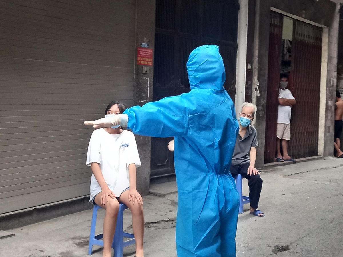 Nhân viên y tế hướng dẫn người dân xếp hàng, chờ đến lượt mình, đảm bảo khoảng cách và các quy định về phòng, chống dịch Covid-19. 