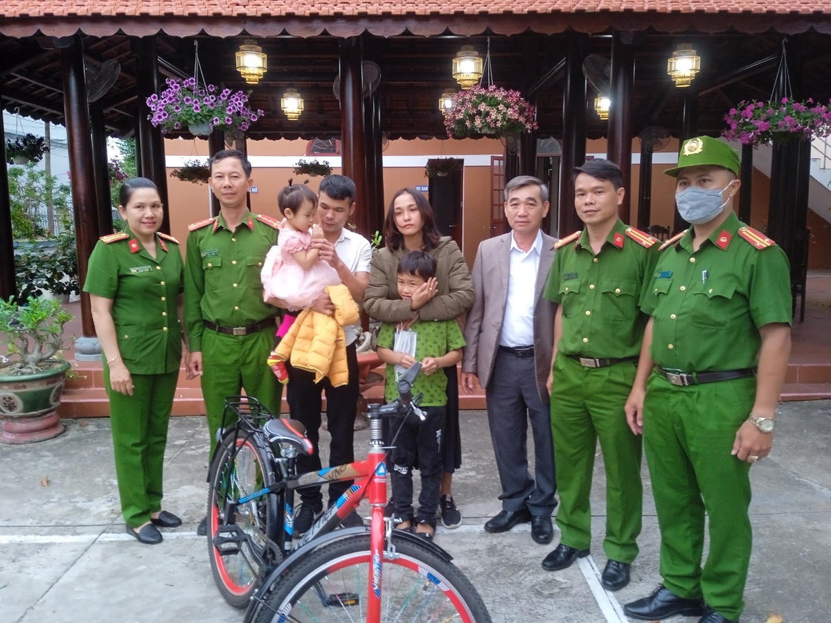 Lực lượng chức năng bàn giao cháu Khánh (ở giữa) về lại với gia đình. 