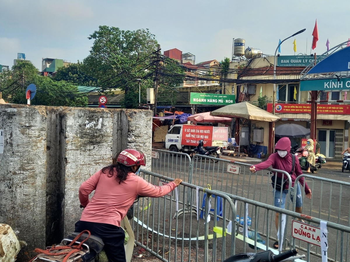 Người dân đưa đồ cho nhau qua 2 lớp hàng rào. 