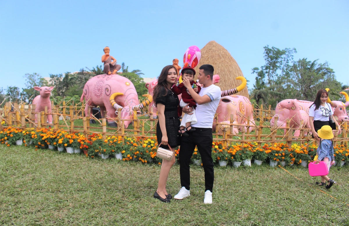 Một gia đình chụp ảnh trước tiểu cảnh có linh vật trâu