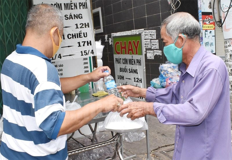 Mạnh thường quân ở Sài Gòn phát cơm cho người nghèo gồm 1 hộp cơm, 1 chai nước suối, 1 quả chuối, người già và trẻ em còn nhận thêm bịch sữa.