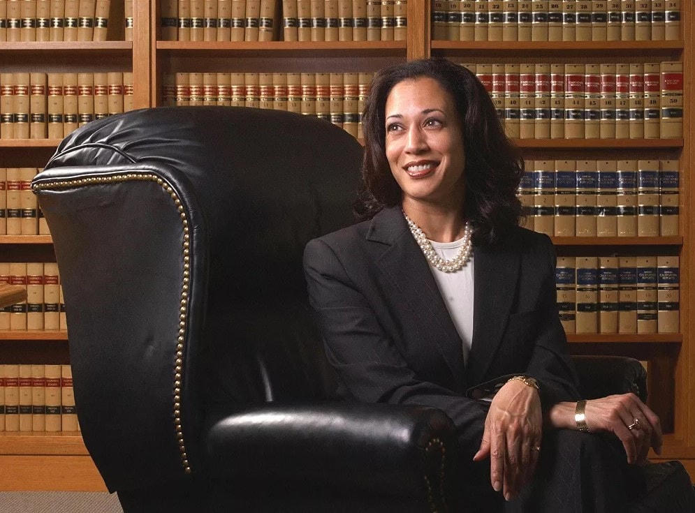 Kamala Harris năm 2004 khi còn là luật sư Quận San trong bộ vest đen, được làm nổi bật bằng một chuỗi ngọc trai trắng và một chiếc áo phông trắng.  