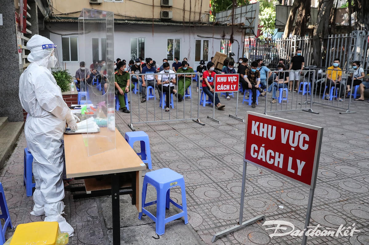 Khu vực xếp hàng và lấy mẫu xét nghiệm được chia 2 khu riêng biêt. Tại khu vực xếp hàng, những người đến tham gia lấy mẫu xét nghiệm thực hiện ngồi giãn cách. Còn phía khu vực lấy mẫu xét nghiệm, cán bộ y tế mặc đầy đủ đồ bảo hộ. Ảnh: Quang Vinh. 