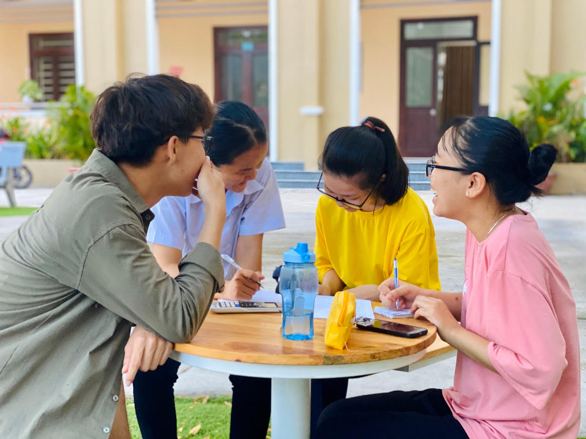Em Quang ngồi trao đổi bài vở với bạn bè tại trường.