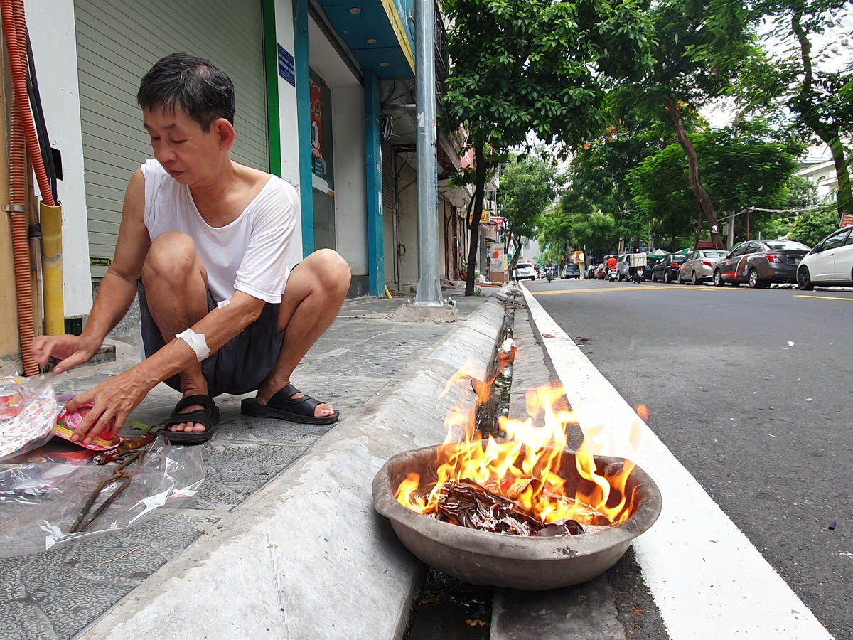Ông Việt đang chăm chú đốt vàng mã trên một góc phố Thụy Khuê.