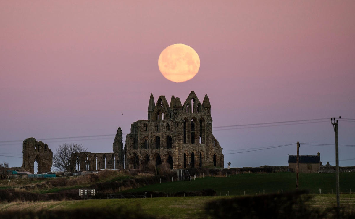 Trăng tròn lặn sau Tu viện Whitby ở Yorkshire. Ảnh: Danny Lawson / PA.