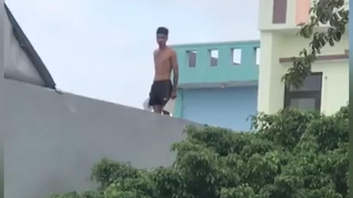 Thanh niên H. leo trên nóc nhà. (Ảnh cắt từ clip).