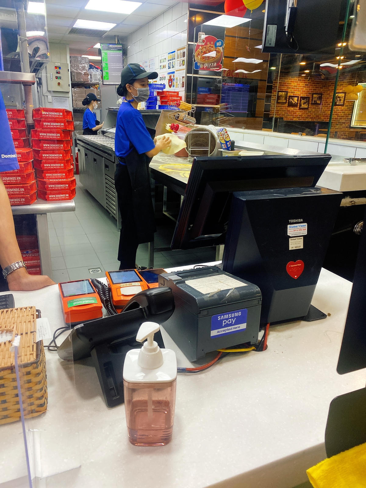 Nhân viên chế biến tại cửa hàng của Domino’s Pizza vô tư dùng tay chế biến bánh cho khác.