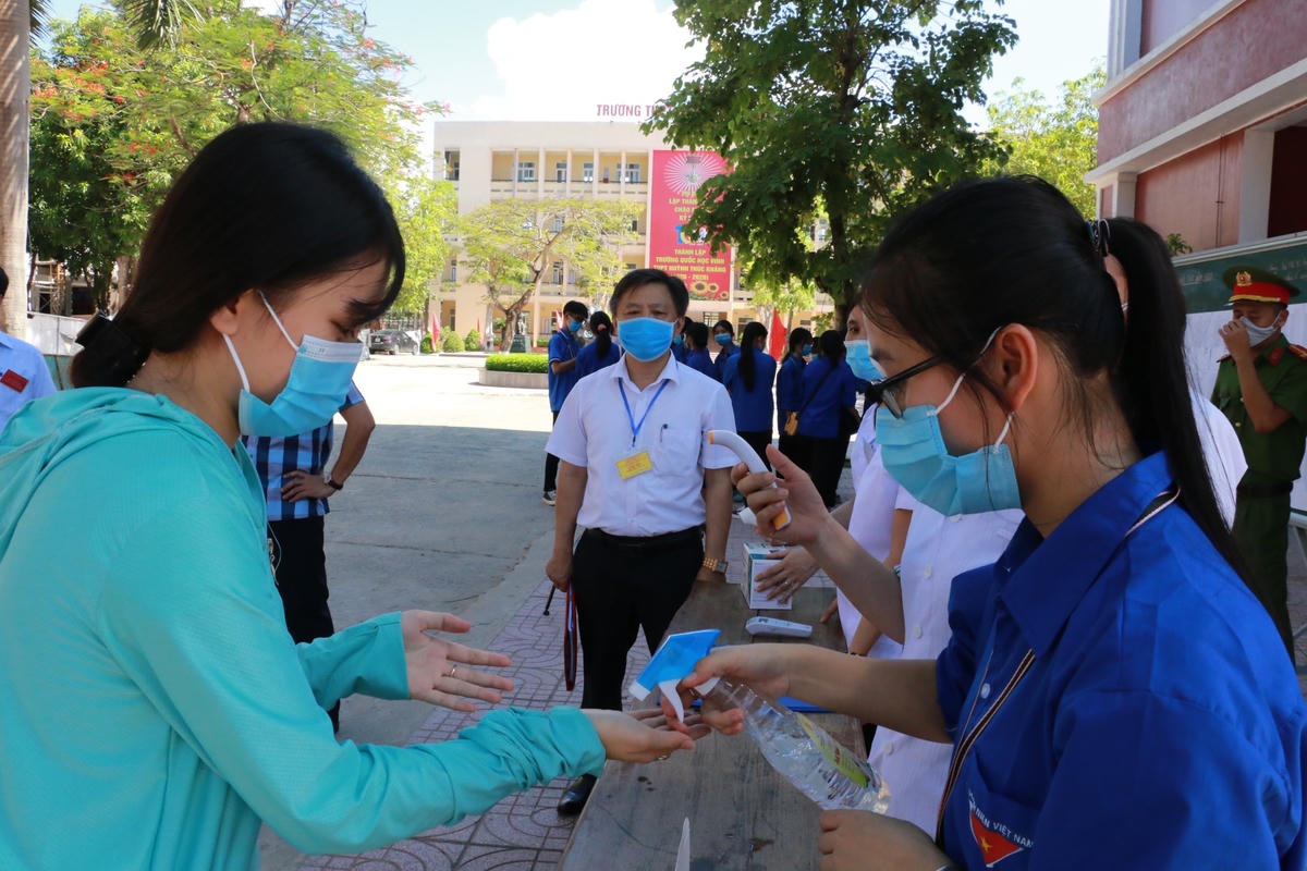 Trước lúc vào phòng thi, tất cả các thi sinh đều phải đo thân nhiệt, đeo khẩu trang và rửa tay khử khuẩn. (Ảnh: Mỹ Hà).
