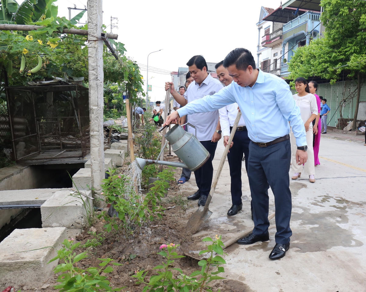 Các đại biểu cùng nhân dân thôn Đức Lân tham gia trồng hoa, cây xanh.