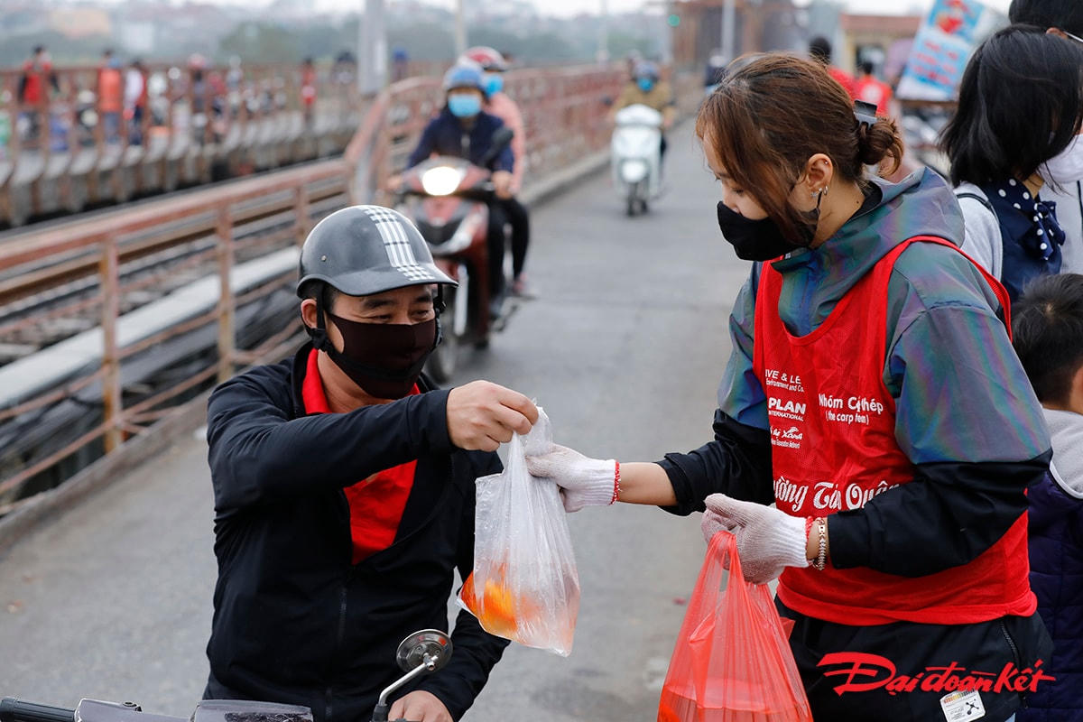Người dân vui vẻ đưa cá chép nhờ các bạn trẻ thả hộ xuống sông.