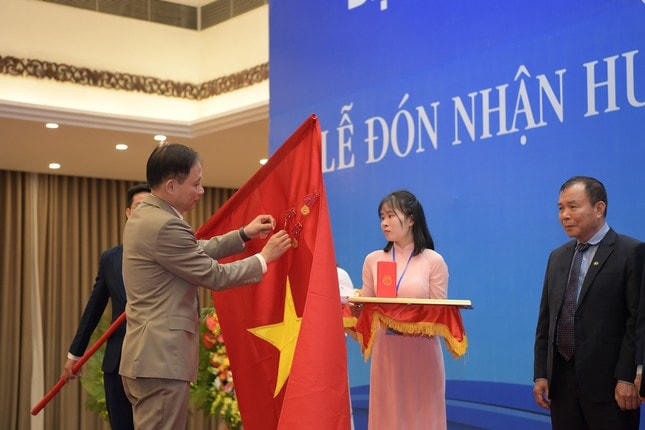 Thứ trưởng Bộ Ngoại giao Lê Hoài Trung gắn Huân chương Lao động hạng Nhất lên Cờ truyền thống của Liên hiệp các Hội UNESCO Việt Nam. Ảnh: ngaynay.vn.