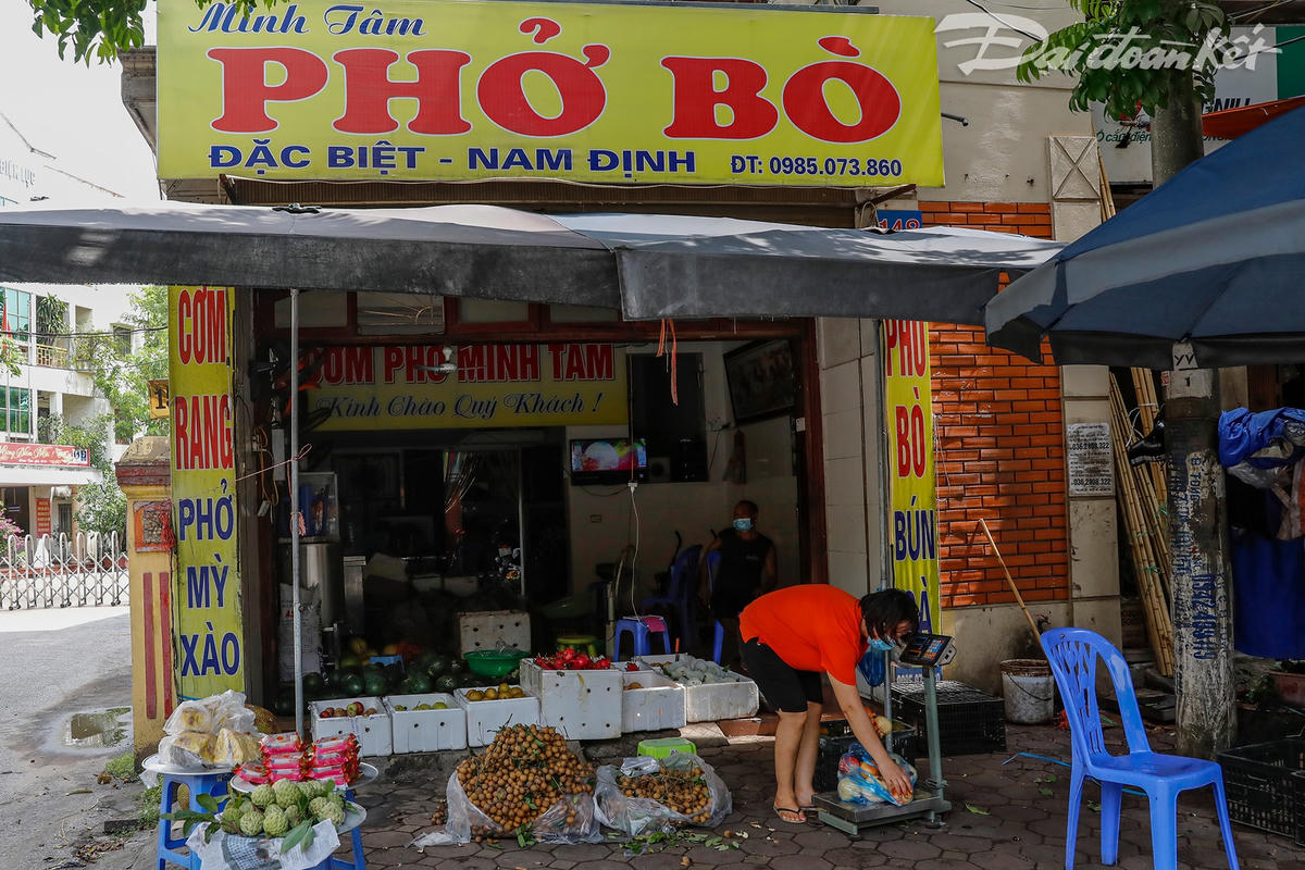 Chị Minh Tâm quê ở Nam Định đã thuê cửa hàng để bán phở bò ở đây được hơn chục năm rồi. Từ đợt giãn cách xã hội chị phải chuyển hướng sang bán hoa quả để duy trì và giảm gánh nặng tiền thuê cửa hàng. Chị nói vài bữa nữa sẽ bán phở trở lại nhưng vẫn bán thêm hoa quả vì sợ thời gian này lượng khách không được đông như trước.