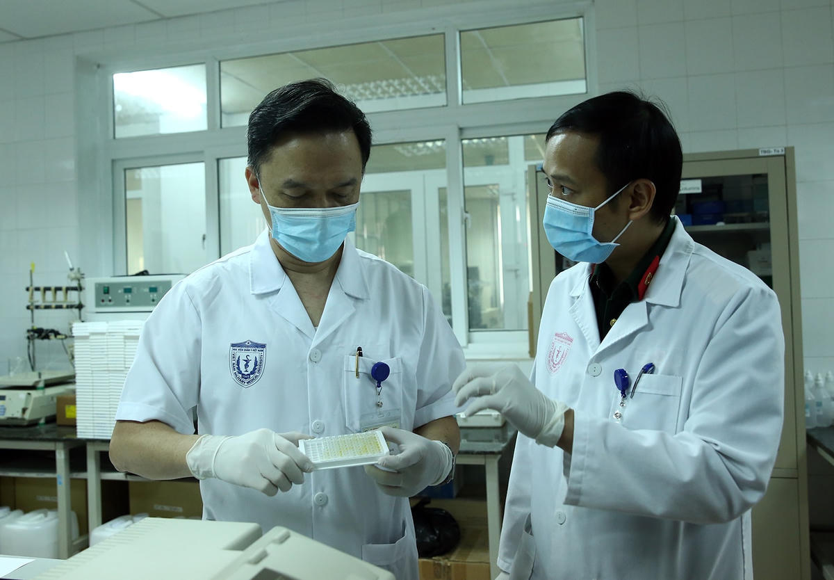 PGS.TS Hồ Anh Sơn (bên trái) xem xét mẫu xét nghiệm sinh kháng thể của các tình nguyện viên tiêm thử nghiệm. Ảnh: Đình Nam.