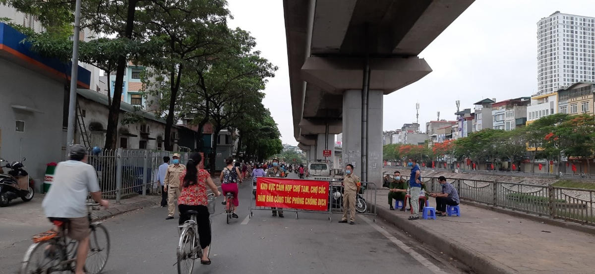 Lực lượng chức năng đặt biển báo cấm họp chợ và ứng trực tại phố Cầu Mới, Ngã Tư Sở (quận Đống Đa), tuy nhiên người dân vẫn ra vào mua bán.