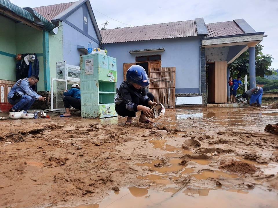 Người dân dọn dẹp bùn đất tại nhà sau lũ.