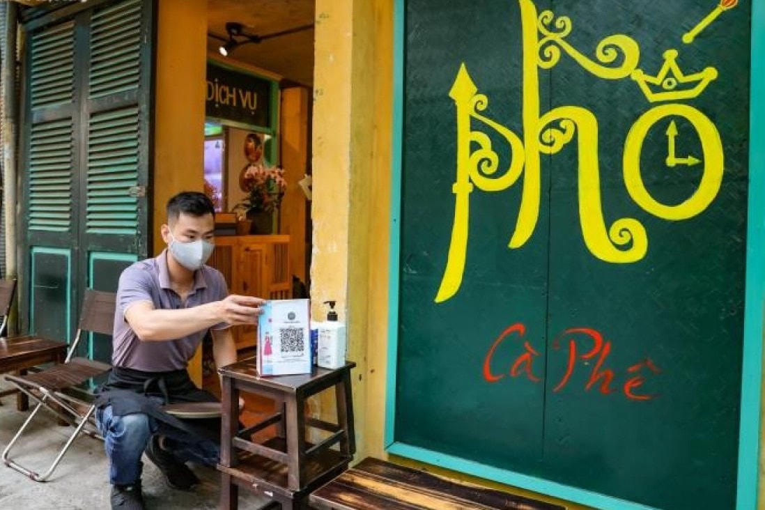 Nhân viên quán cà phê ở gần phố đi bộ Hồ Gươm chuẩn bị nước rửa tay sát khuẩn và bảng QR-code để khách hàng khai báo y tế phòng dịch bệnh. ảnh: vtc new