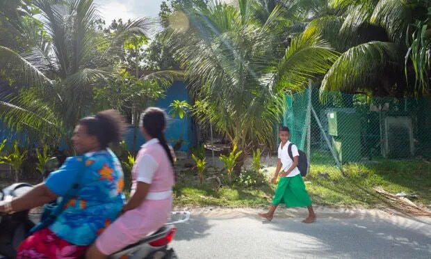 Một cậu bé đi bộ từ trường về nhà ở thủ đô Funafuti của Tuvaluan. Ảnh: Sean Gallagher / The Guardian.