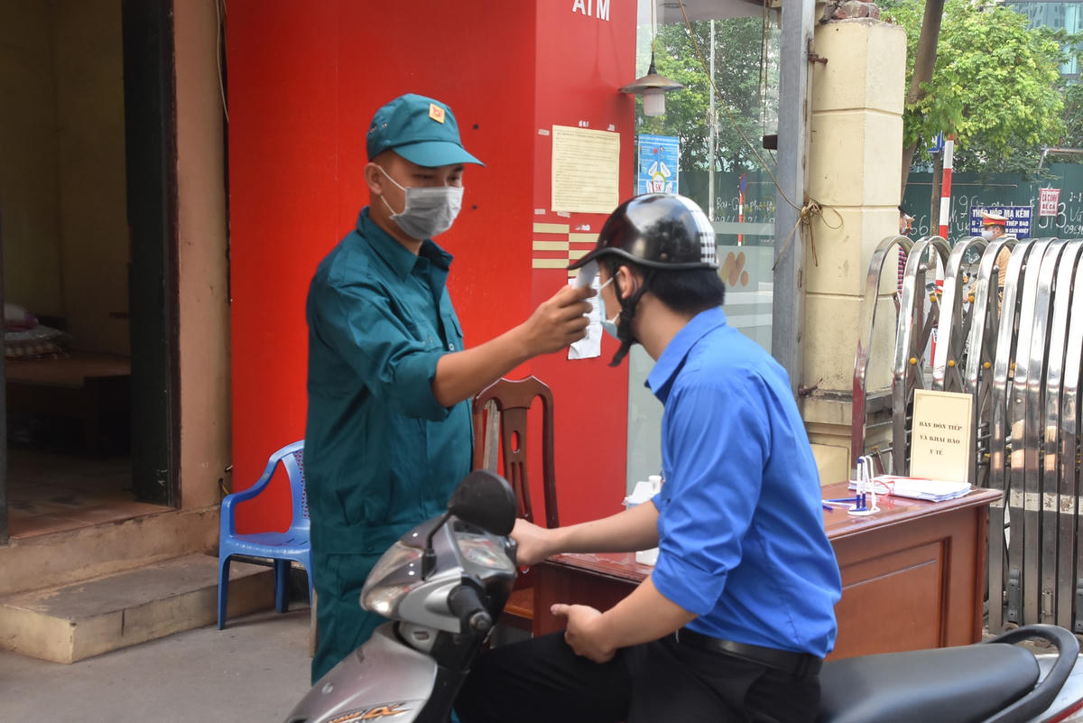 Lực lượng dân phòng thực hiện đo thân nhiệt cho các cử tri tham gia bỏ phiếu.