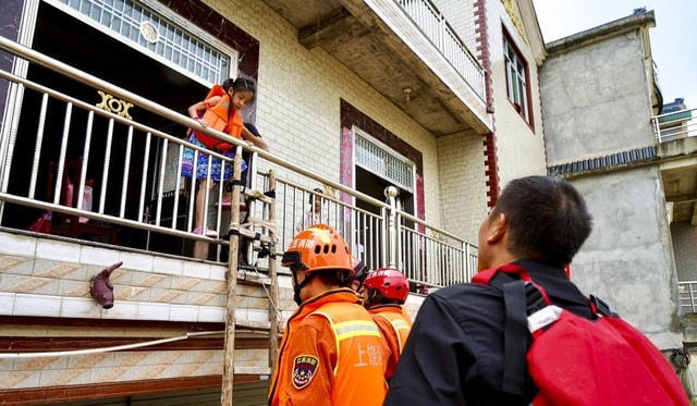 Lính cứu hỏa giải cứu bé gái bị mắc kẹt vì lụt (Ảnh: SCMP).
