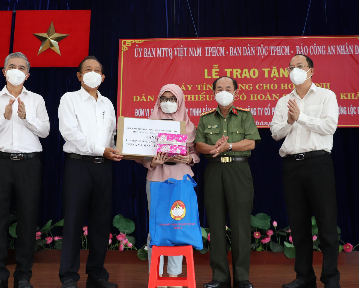 Nguyên Phó Thủ tướng Thường trực Trương Hòa Bình và đại diện Ban tổ chức trao máy tính bảng cho một em học sinh.