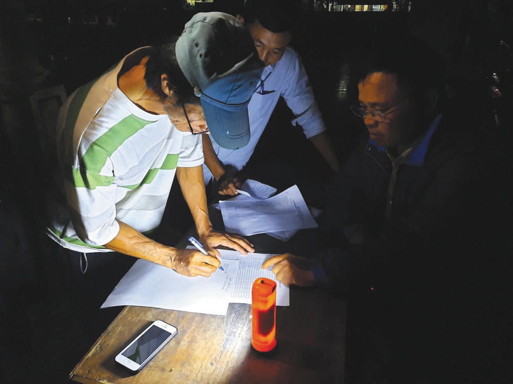 Các thành viên Ban Công tác Mặt trận và Trưởng thôn Vinh Quang, xã Sơn Thủy, huyện Lệ Thủy, tỉnh Quảng Bình lên danh sách các hộ dân bị thiệt hại do lũ ngay trong đêm. Ảnh: Q.Nghĩa.