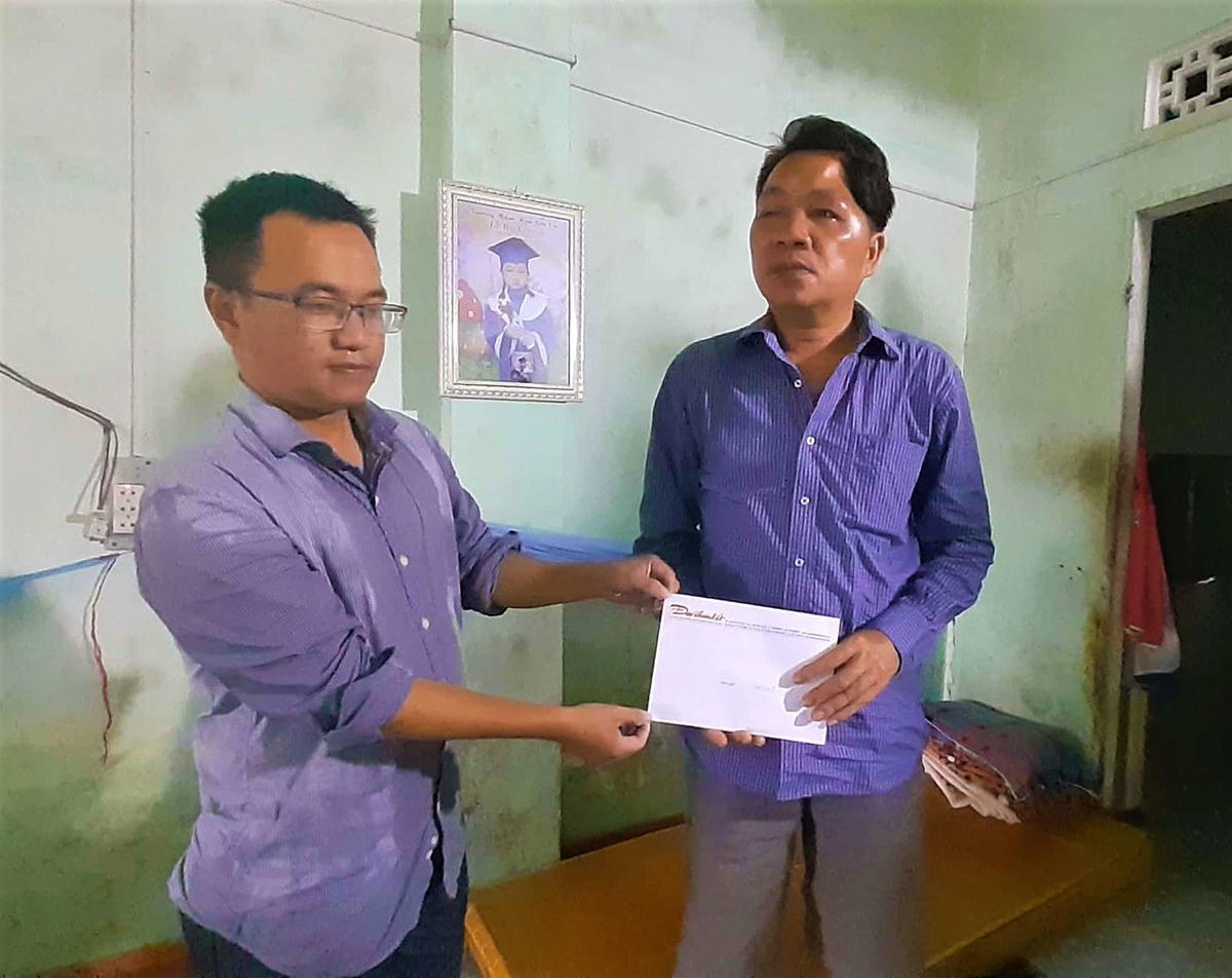 Đại diện VP báo Đại Đoàn Kết (bên trái) trao tiền hỗ trợ của bạn đọc cho ông Bùi Đình An.