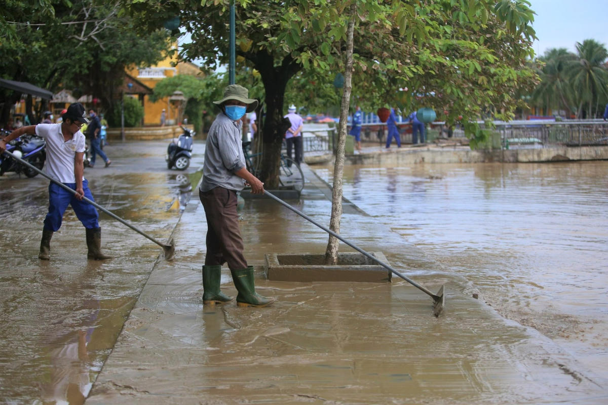 Người dân dọn dẹp bùn đất trên đường Bạch Đằng.