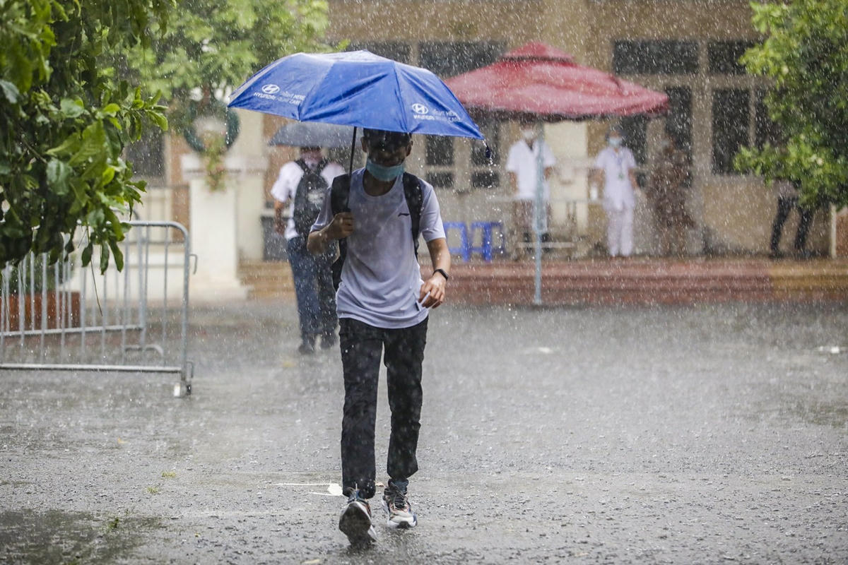 Thí sinh đội mưa đến trường thi (ảnh Phạm Quang Vinh).
