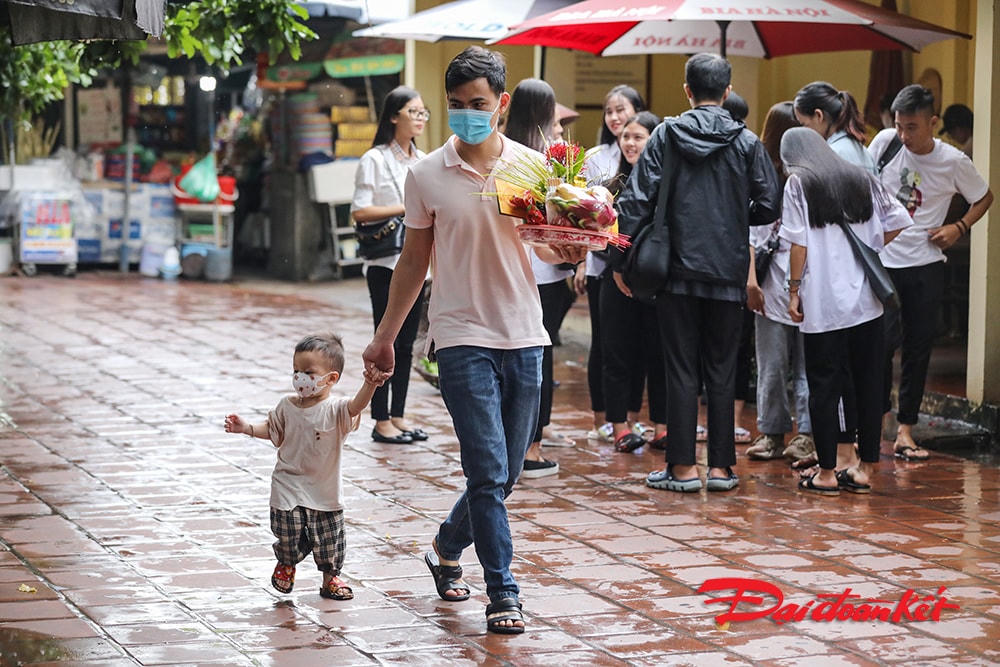 Hình ảnh 2 bố con đi lễ đeo khẩu trang chấp hành đúng quy định có vẻ tương phản hoàn toàn với những bạn trẻ phía sau.