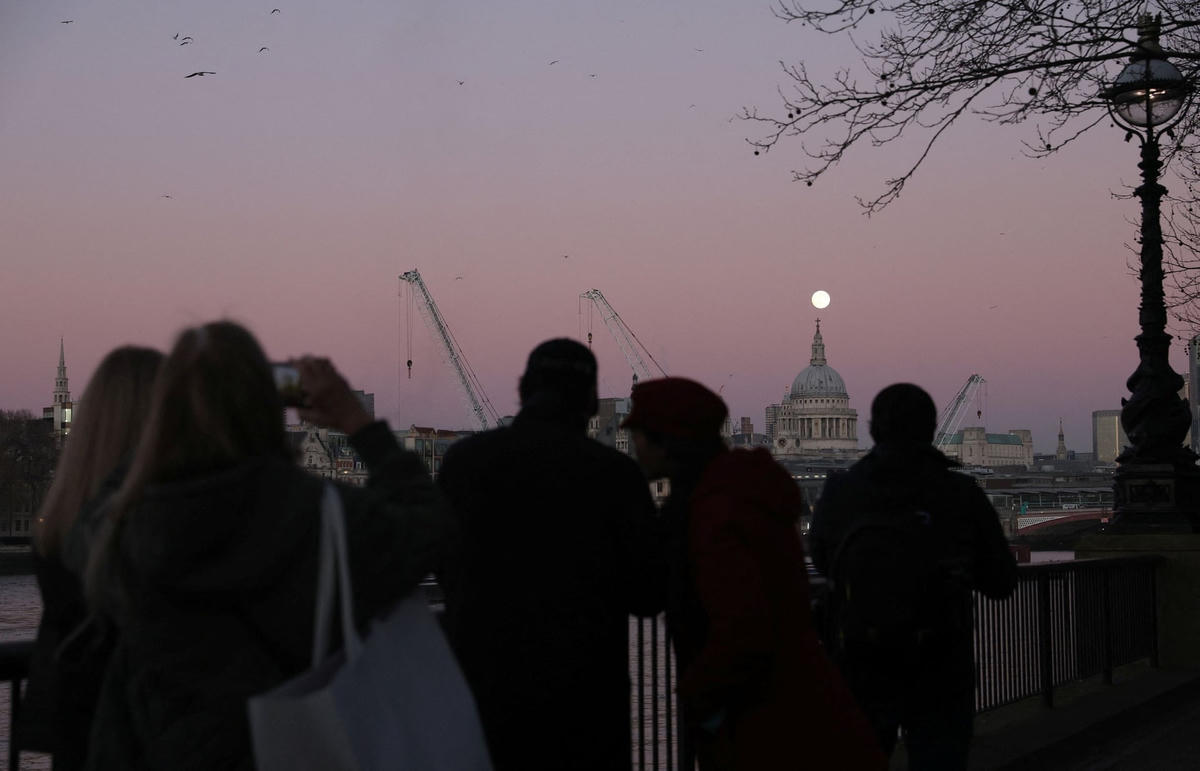 Cảnh tượng người dân chụp lại khoảnh khắc Trăng Sói xuất hiện trên bầu trời London, phía ngoài nhà thờ St Paul. Ảnh: Hannah McKay / Reuters.
