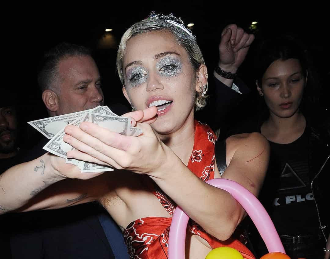 Bị bắt ra khỏi hộp đêm, Miley Cyrus đã đánh lạc hướng các tay săn ảnh bằng cách “tắm” cho họ bằng tiền mặt.  
