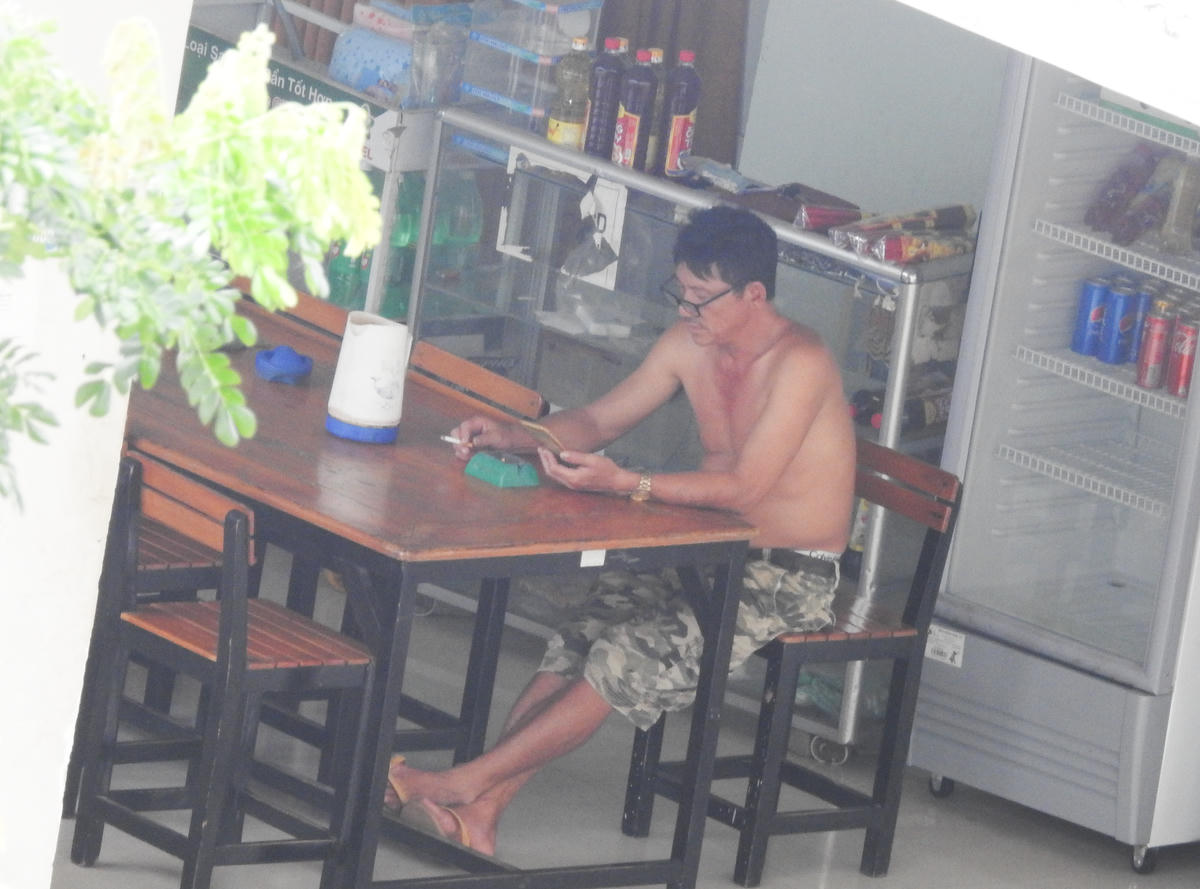Ông Phúc, Nhà trưởng nhà A luôn không đeo khẩu trang, ở trần ngồi uống bia, hút thuốc tại căn tin của tòa nhà - nơi luôn có nhiều người qua lại. (Ảnh chụp chiều 30/8)