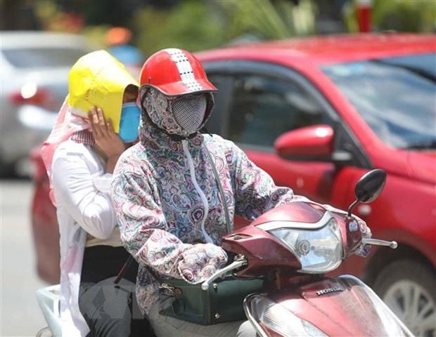 Thời điểm giữa trưa, nếu phải di chuyển trên đường, người dân cần trang bị đồ chống nắng để đảm bảo sức khỏe.  Ảnh: TTXVN.