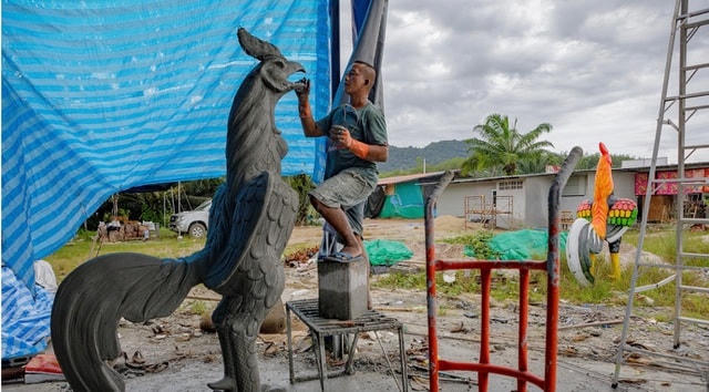 Một người đàn ông đang tiến hành đúc tượng gà.