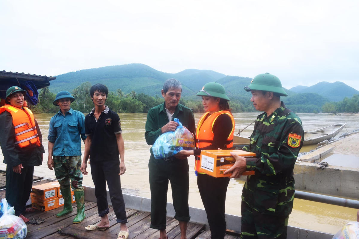 Nữ cán bộ Mặt trận xông pha trên nước lũ để trao tận tay quà cứu trợ cho người dân.