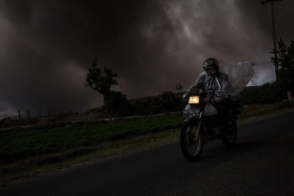 ​15. Người đàn ông trên chiếc xe máy khi núi Sinabung phun tro, nhìn từ làng Tiga Kicat ngày 20 tháng 06 năm 2015. Ảnh Ulet Ifansasti / Getty. 