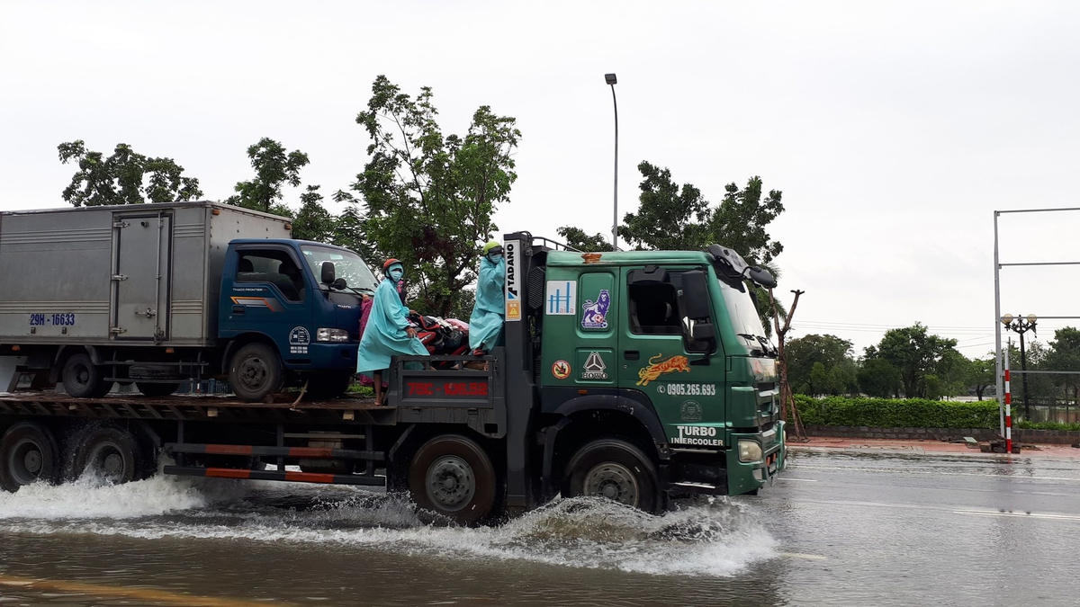 Nhiều người và phương tiện phải đi nhờ xe để qua vùng nước ngập.