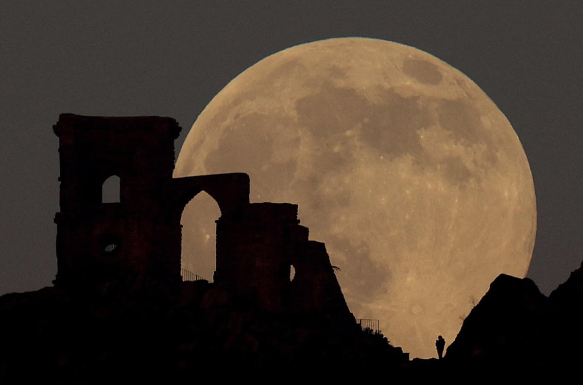 Trăng Sói huyền bí lấp ló đằng sau tàn tích cổ Mow Cop Folly ở Cheshire, Anh. Ảnh: Carl Recine / Reuters.