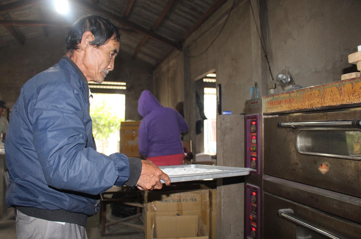 Ông Đinh Xuân Cầm đang cho bánh in vào lò nấu.